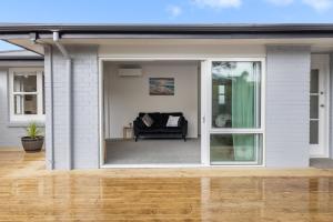 eine Glasschiebetür auf einem Haus mit einer Couch in der Unterkunft Restful Retreat in Tauranga