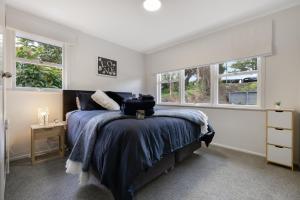 a bedroom with a bed and two windows at Restful Retreat in Tauranga