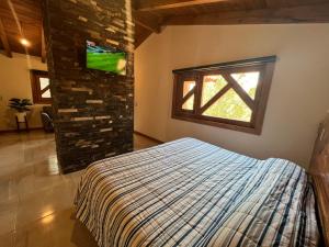een slaapkamer met een bed en een tv aan de muur bij Cabaña Lunamiel 3 in Mazamitla