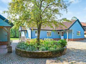 een blauw huis met een boom ervoor bij Pear Tree Cottage in Southburgh