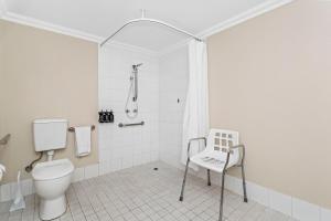 a bathroom with a toilet and a chair in it at Stylish Urban Gem Downtown Perth in Perth +14 photos
