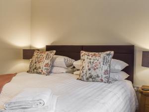 a bed with white sheets and pillows in a bedroom at Ivy Cottage in Dent
