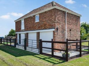 a brick house with a garage and a fence at The Coach House in New Bolingbroke