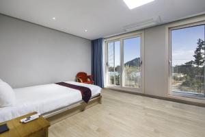 a bedroom with a bed and large windows at The Bay Jeju Resort in Seogwipo