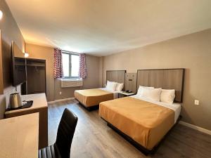 una camera d'albergo con 2 letti e una scrivania di Regal Inn & Suites New York LaGuardia Hotel a Flushing