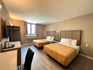 a hotel room with two beds and a desk at Regal Inn & Suites New York LaGuardia Hotel in Flushing
