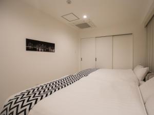 Un dormitorio blanco con una gran cama blanca. en BIG ROOM GUEST HOUSE / Vacation STAY 3493, en Osaka
