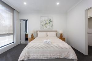 een slaapkamer met een wit bed en 2 handdoeken bij Westside Retreat in Perth