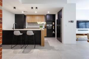 a kitchen with black cabinets and white counter tops at Westside Retreat in Perth