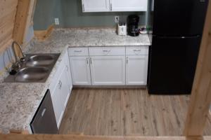 a kitchen with white cabinets and a black refrigerator at Sunrise Shore in Au Gres