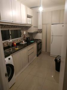 cocina con armarios blancos y lavadora en Hermoso Apto de 3 Dormitorios 86m2 en Tres Cruces en Montevideo