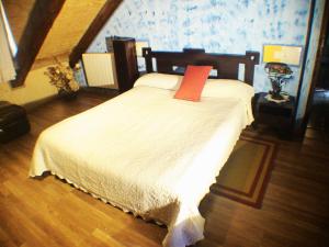 a bedroom with a bed with a red pillow on it at Casa del Cura in Rozas