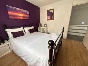 a bedroom with a large bed with purple walls at Home from home, close to Redditch hospital & transport links in Redditch
