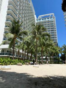 a beach with palm trees in front of a building at Velvet Waves in Manila