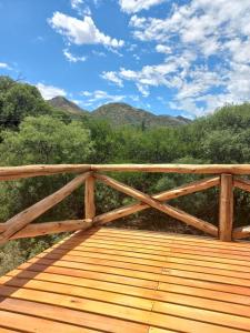 uma ponte de madeira com montanhas ao fundo em Cabaña La Yumba em Capilla del Monte