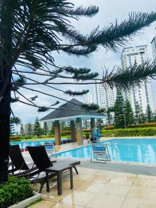a pool with two chairs and a table and an umbrella at Wind Residences Apt. 1506 Tagaytay in Tagaytay