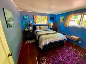 1 dormitorio con 1 cama con paredes azules y alfombra en Ocean Park Beach Cottage en Ocean Park