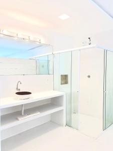 ein weißes Bad mit einem Waschbecken und einer Dusche in der Unterkunft Villa Jundu in São Miguel do Gostoso
