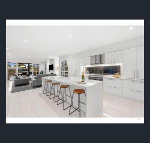 a kitchen with white cabinets and bar stools at St Georges Luxury Beach House in Torquay