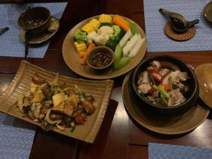 tres platos de comida en una mesa de madera en Suha Villa- Flamingo Dai Lai Resort, en Phúc Yên