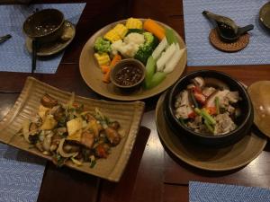 three plates of food on a wooden table at TD Villa- Dai Lai Resort in Phúc Yên