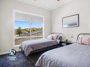 a bedroom with two beds and a large window at Brand New 3 Bed 2 Bath with Sea Views in Encounter Bay