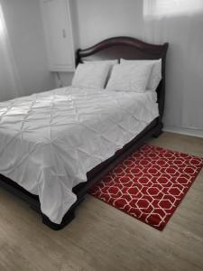 - un lit avec une couette blanche et un tapis rouge dans l'établissement Sheena palace, à Gatineau
