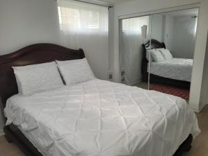 een slaapkamer met een groot wit bed en een spiegel bij Sheena palace in Gatineau