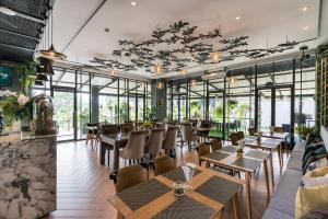 un restaurante con mesas, sillas y ventanas en The Siamese Hotel by PCL en Pattaya North