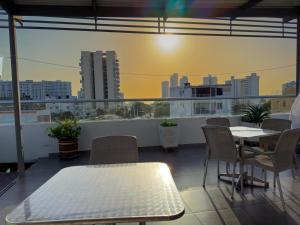 a balcony with tables and chairs and a view of a city at Hotel Zamay Gaira in Santa Marta