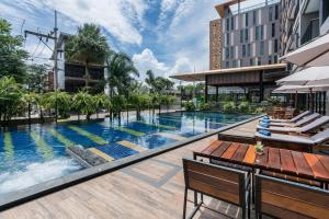 an outdoor pool at a hotel with chairs and a table at The Siamese Hotel by PCL in Pattaya North