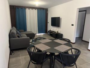 a living room with a table and chairs and a tv at APPARTEMENT T3 COSY et PAISIBLE avec JARDIN à REMIRE-MONTJOLY in Rémiré