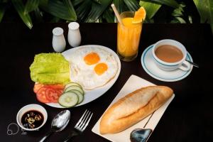 a plate of eggs and bread and a cup of coffee at Hoi An Blue River Hotel in Hoi An