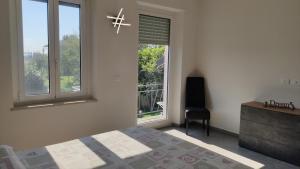 ein Schlafzimmer mit einem Bett, einem Fenster und einem Stuhl in der Unterkunft Villa Fiorita in San Maurizio Canavese