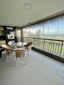 a dining room with a table and chairs and a balcony at Apartamento Manhattan Beach Riviera in Aquiraz
