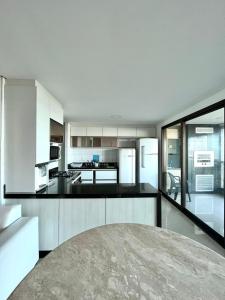 a kitchen with white cabinets and black counter tops at Apartamento Manhattan Beach Riviera in Aquiraz +18 photos