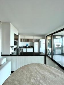 a kitchen with white cabinets and black counter tops at Apartamento Manhattan Beach Riviera in Aquiraz