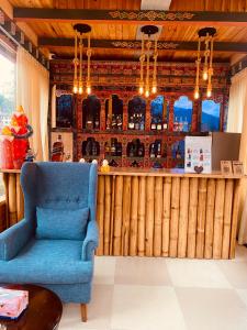 a living room with a blue chair and a bar at Lhayhuel Resort and Spa in Paro