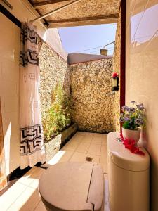 een badkamer met een toilet en een stenen muur bij Penida Hills in Nusa Penida