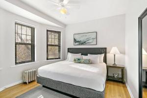 a white bedroom with a bed and two windows at Beautiful 1BR Brick Home in Historic Hyde Park in Chicago