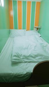 a large white bed with an orange and green headboard at Ruby Star Hostel Dubai loft Beds G in Dubai