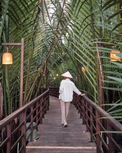 a woman walking down a bridge with a hat on at Hoi An Eco Lodge & Spa in Hoi An