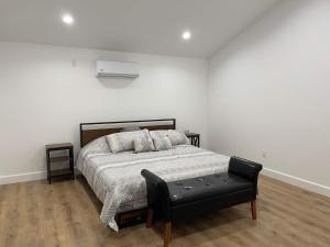 a white bedroom with a bed and a black stool at Gated private house with own parking Sherman Oaks in Los Angeles