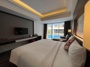 a bedroom with a large white bed and a tv at Arshika Bali Sunset Road in Kuta