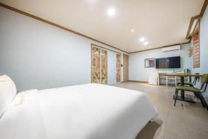 a bedroom with a white bed and a desk at Sugar Motel in Gunsan