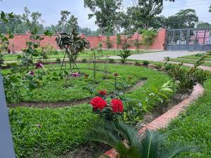 un giardino con fiori rossi di fronte a un edificio in mattoni di Yahiya a Sylhet