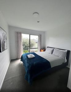 a bedroom with a large bed with a large window at Kapanga Escape in Coromandel Town