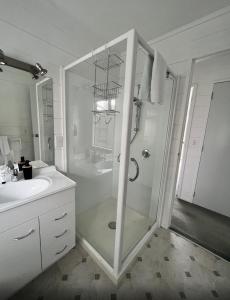 a white bathroom with a shower and a sink at Kapanga Escape in Coromandel Town