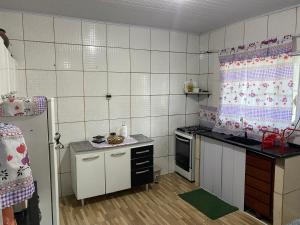 a small kitchen with a white tiled wall at Chácara dos Silva in Santa Isabel +19 photos