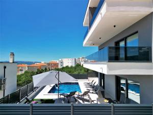 einen Balkon mit einem Pool, Stühlen und einem Sonnenschirm in der Unterkunft Villa Adria in Makarska